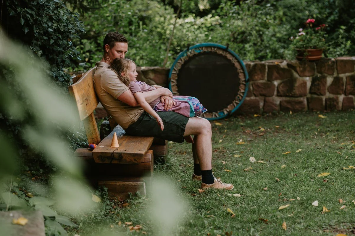 Vater und Schulkind genießen gemeinsamen Moment auf der Bank im Grünen beim Einschulung feiern in der Pfalz.