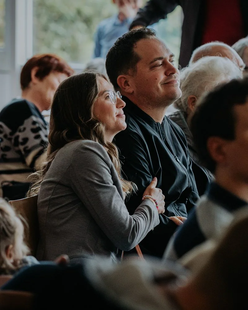Eine Mama und ein Papa schauen emotional zu ihrem Schulkind während der Einschulungsfeier.