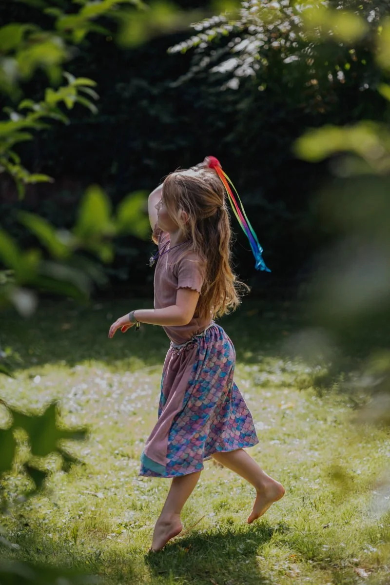 Schulkind spielt mit Ball mit bunten Bändern im Garten beim fröhlichen Einschulung feiern in der Pfalz.