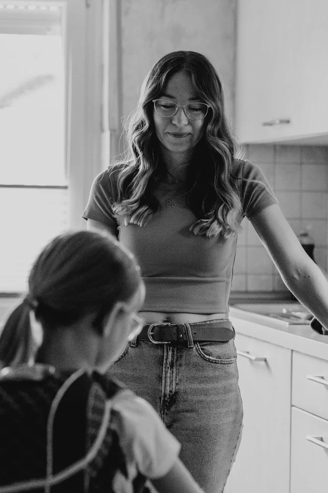 Eine Mama ist emotional mit Freudentränen, während sie ihr Kind mit Schultüte und Schulranzen betrachtet.