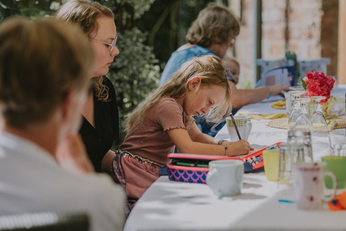 Erstes Hausaufgaben-Erlebnis: Schulkind sitzt auf Schoß am gedeckten Tisch beim fröhlichen Einschulung feiern in der Pfalz.