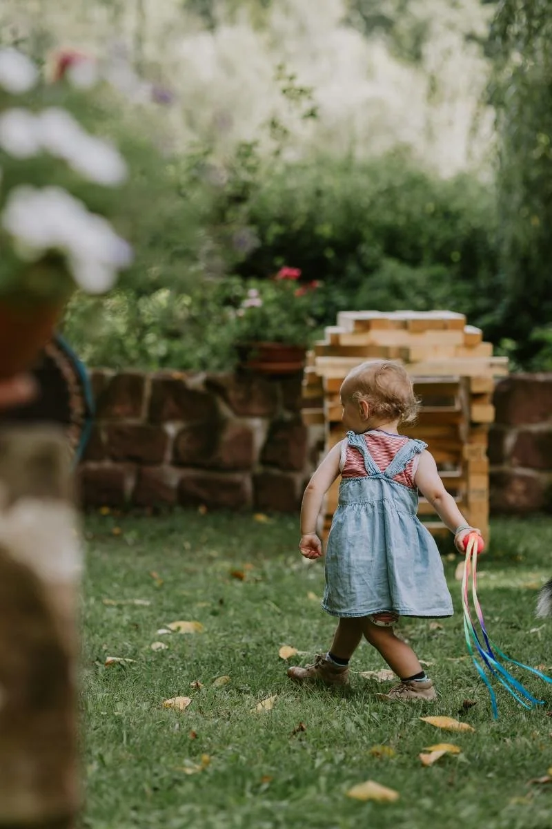 Kleines Mädchen nimmt viel Schwung, um einen Ball zu werfen beim fröhlichen Einschulung feiern in der Pfalz.
