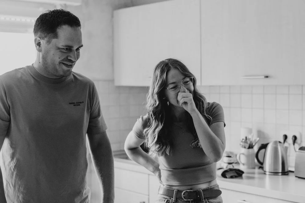 Ein Vater und eine Mutter stehen in der Küche. Die Mutter wirkt emotional und sehr gerührt, hat Tränen in den Augen.