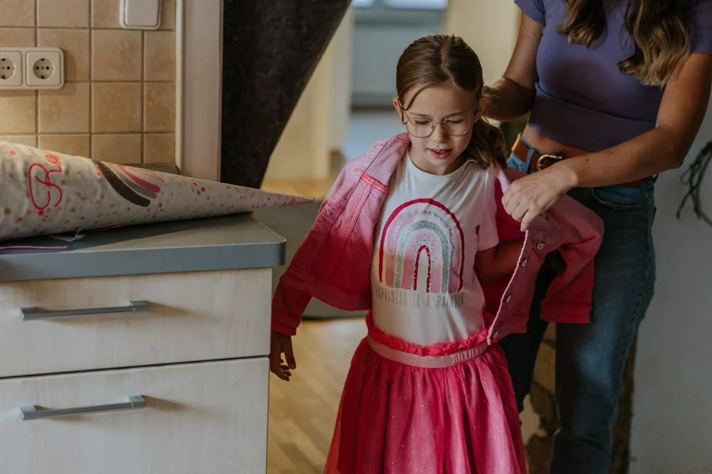 Ein Schulkind zieht sich eine schicke Jacke für die Einschulungsfeier an.