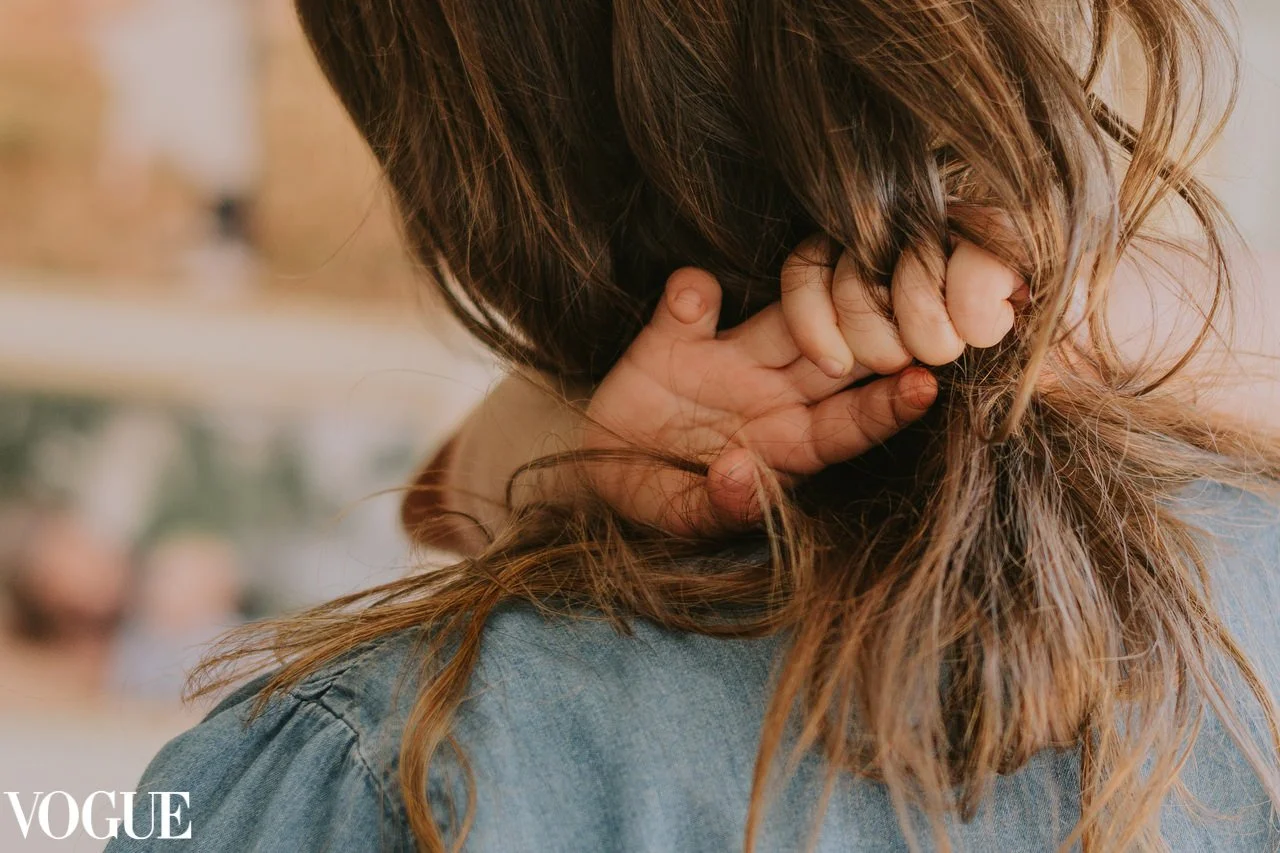 Detailaufnahme: Ein Kind umarmt seine Mutter, die verschränkten Hände liegen im Haar der Mutter. Ein stiller Moment voller Nähe und Verbundenheit
