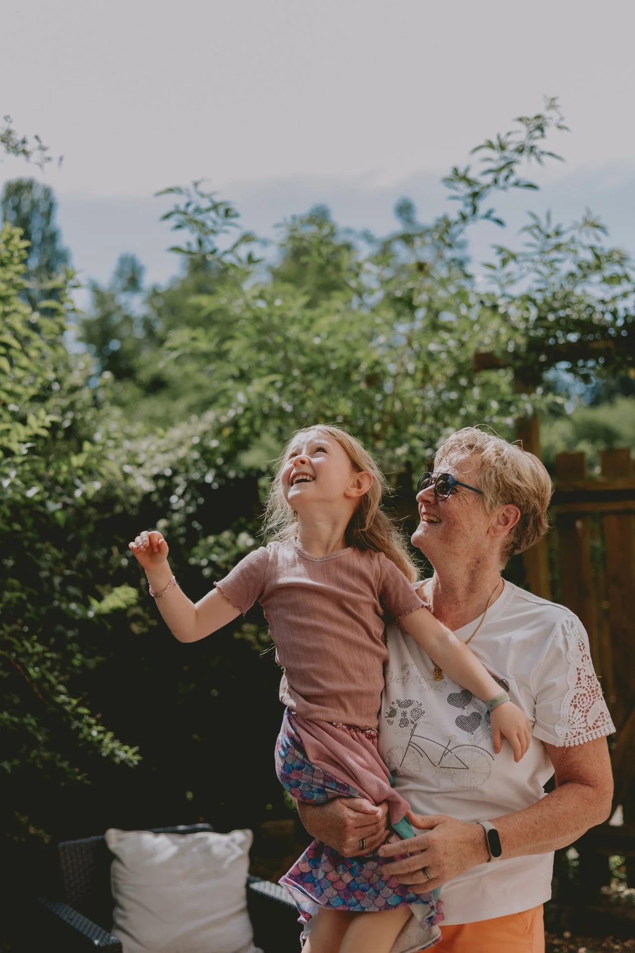 Oma hält Schulkind auf dem Arm, beide blicken nach oben voller Freude beim Einschulung feiern in der Pfalz.