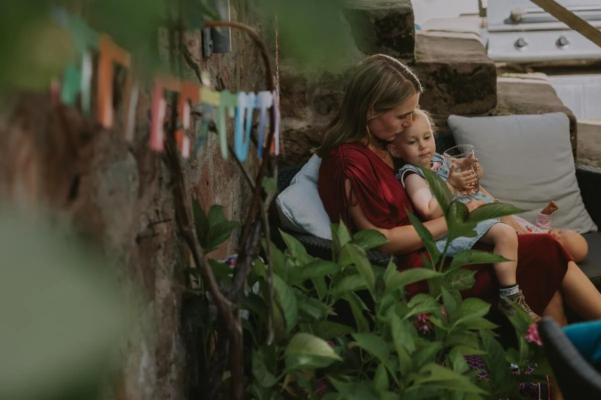Mutter hält Kind auf dem Schoß, dekorative Girlande im Vordergrund beim Einschulung feiern in der Pfalz.