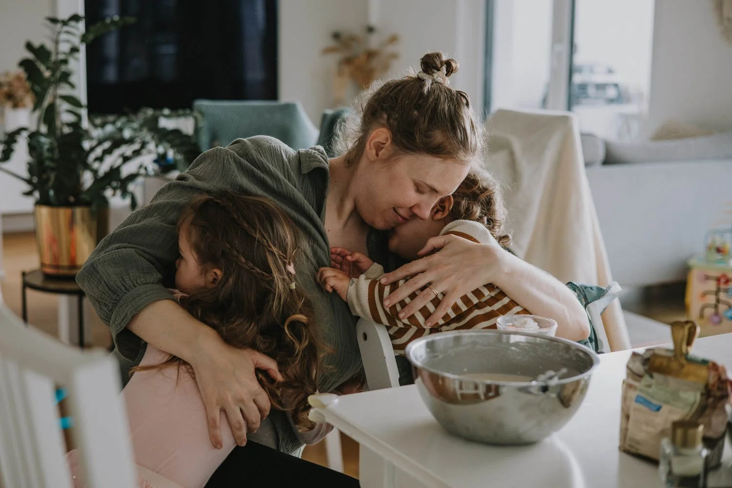 Natürliche Familienfotografie fängt Umarmung ein zwischen Mama und Kindern.
