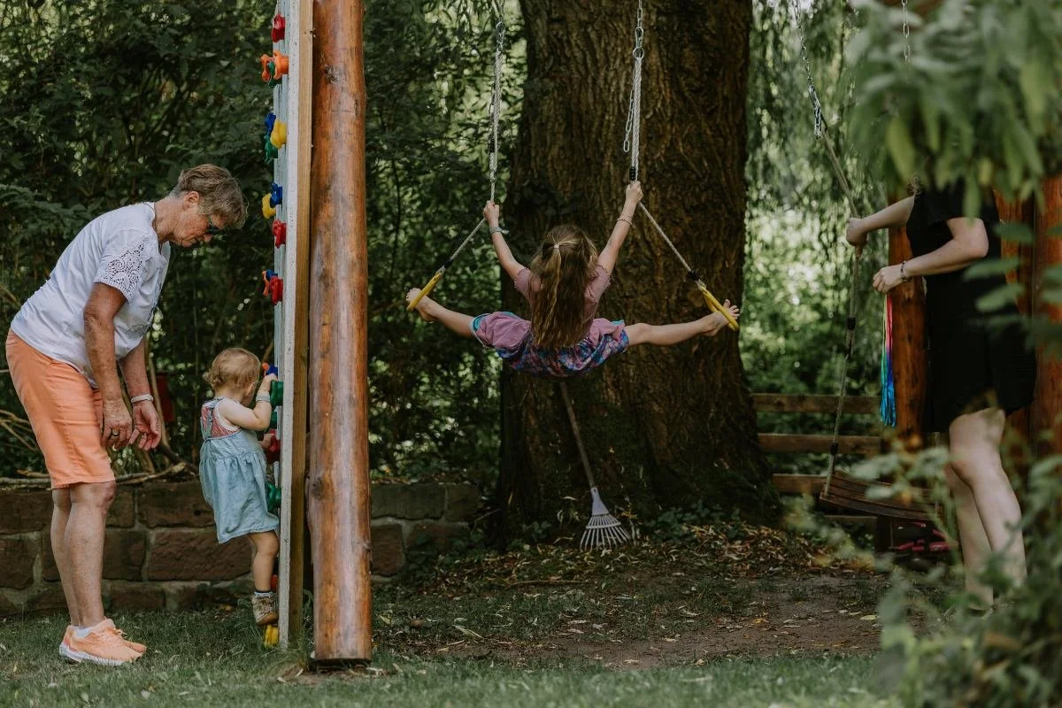 Oma, Kleinkind und Schulkind aktiv am Klettergerüst im Garten beim fröhlichen Einschulung feiern in der Pfalz.