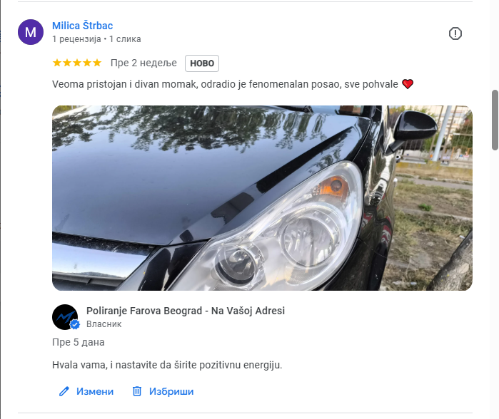 Close-up of a black car's headlight and part of the hood, with reflections on the shiny surface.