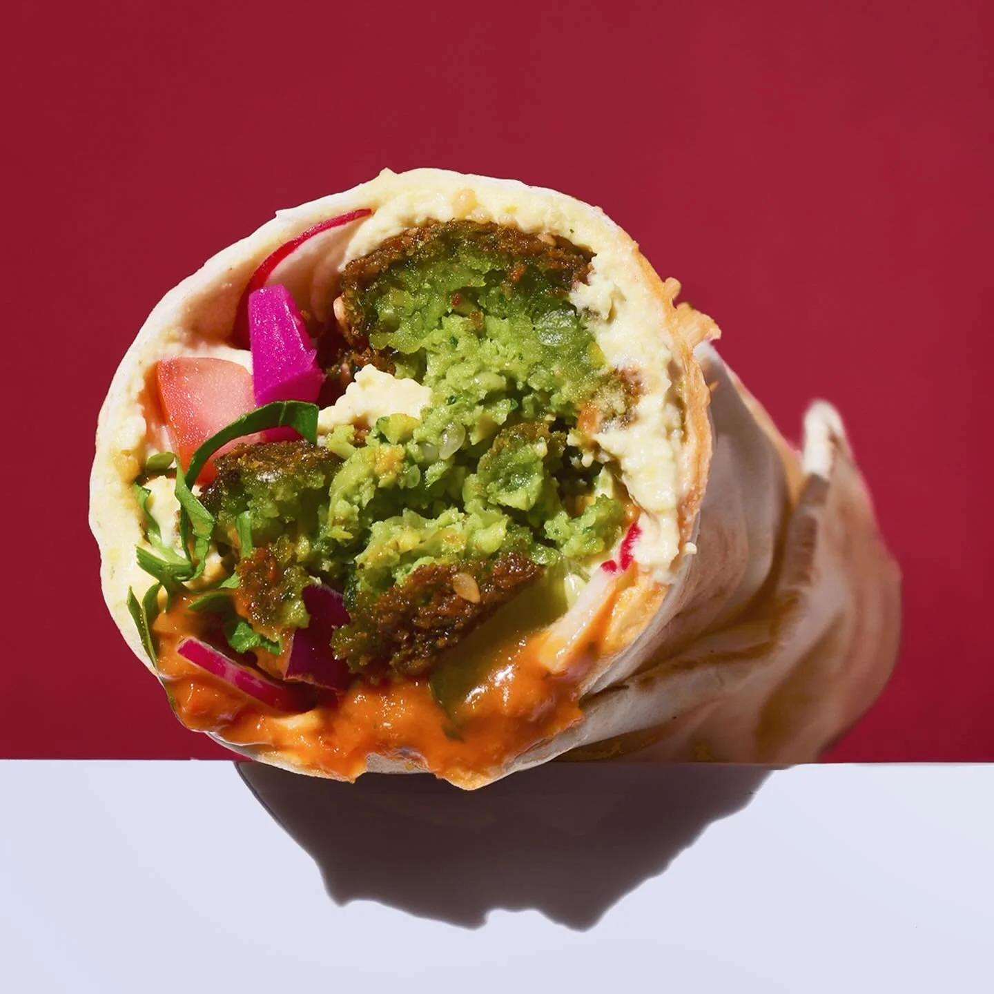 Say hi to our Falafel &amp; Hummus Wrap. Falafel, creamy hummus, and spicy chilli sauce in a toasted handmade flatbread. Loaded with pickled turnips, fresh radish, pomegranate seeds, and tahini.