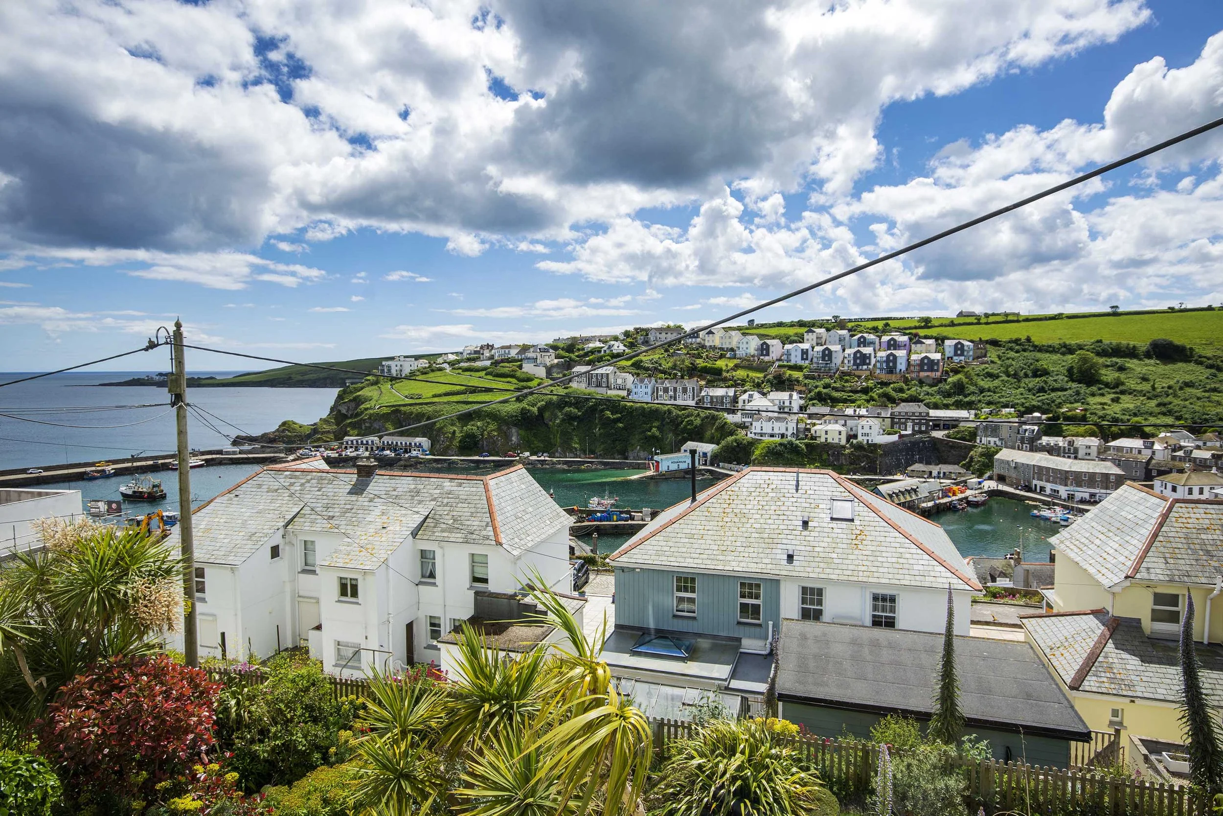 View from the top window of Seafarers cottage overlooking houses in the foreground and Mevagissey harbour beyond them. 