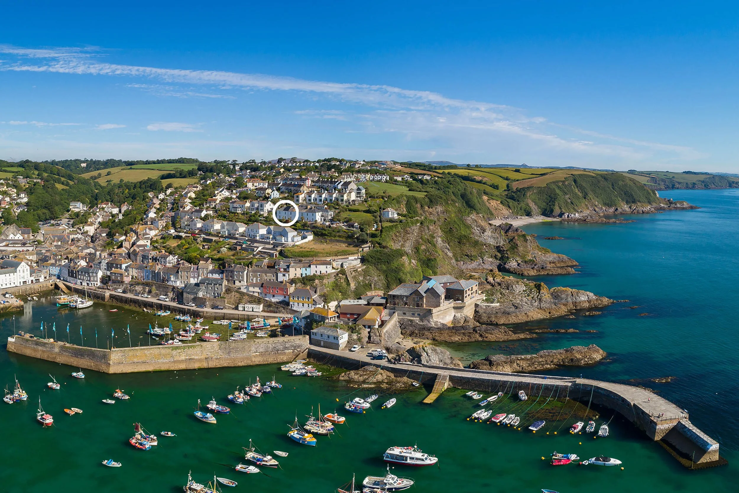 View of Mevagissey harbour with houses and cottages up the hillside away from the harbour. Seafarers cottage is circled to identify it.