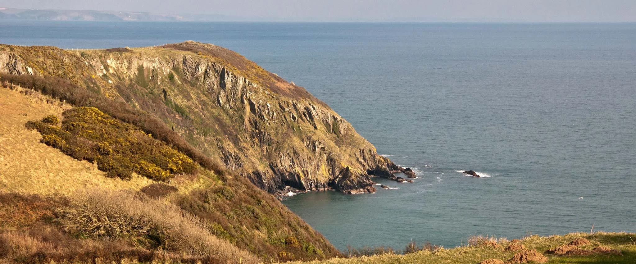 View from the cliff path between Mevagissey and Gorran Haven with stunning cliffs and sea views beyond.