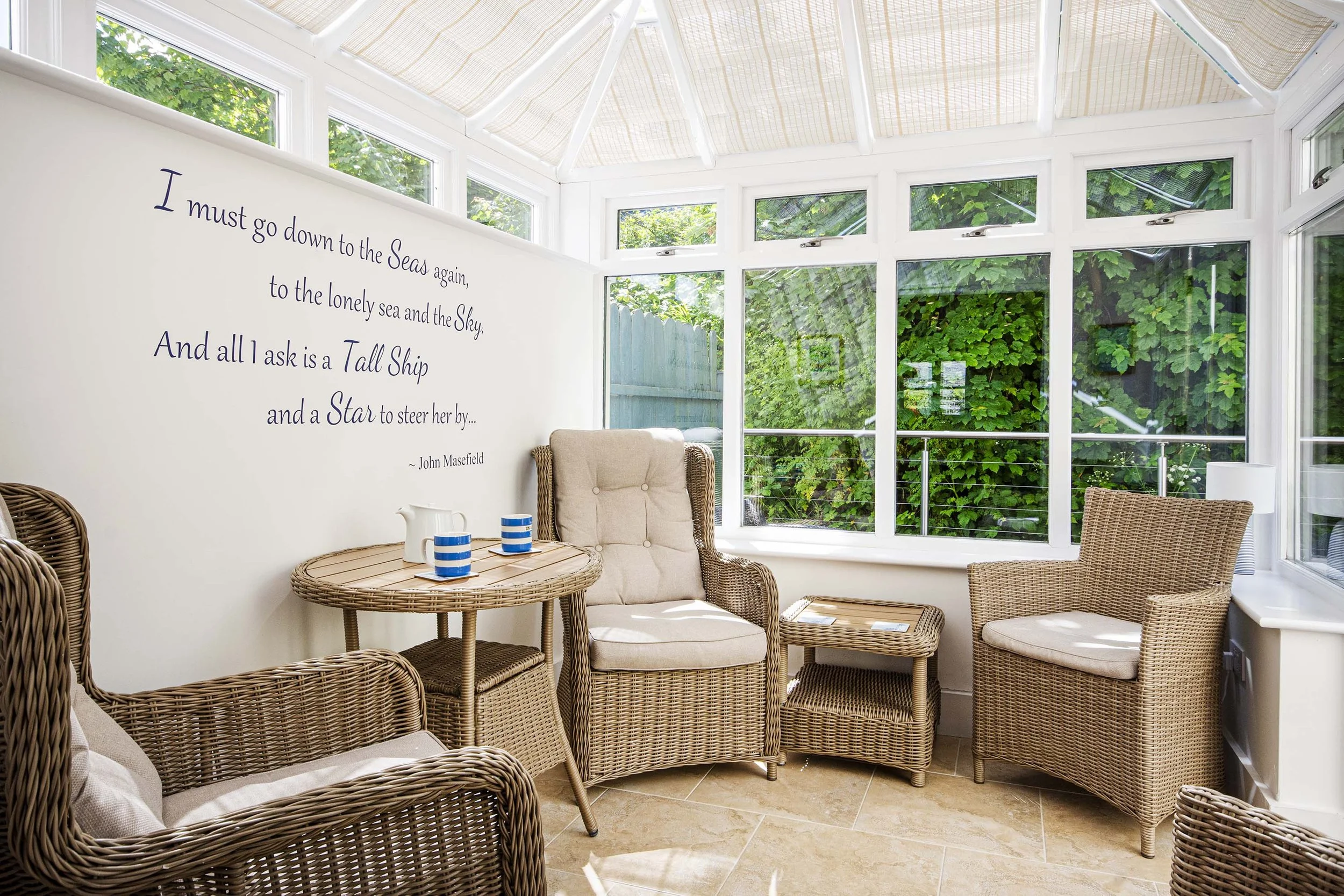 View of the conservatory with wicker seating and cushions.
