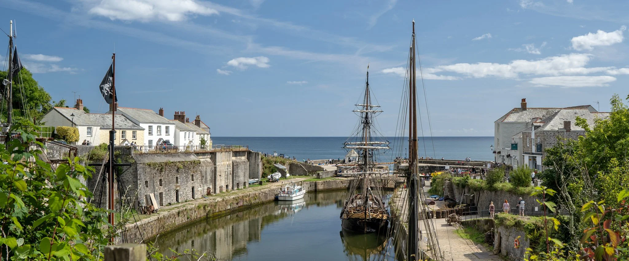 View looking out to sea at Charlestown Harbour with tall ships moored by the quayside. 