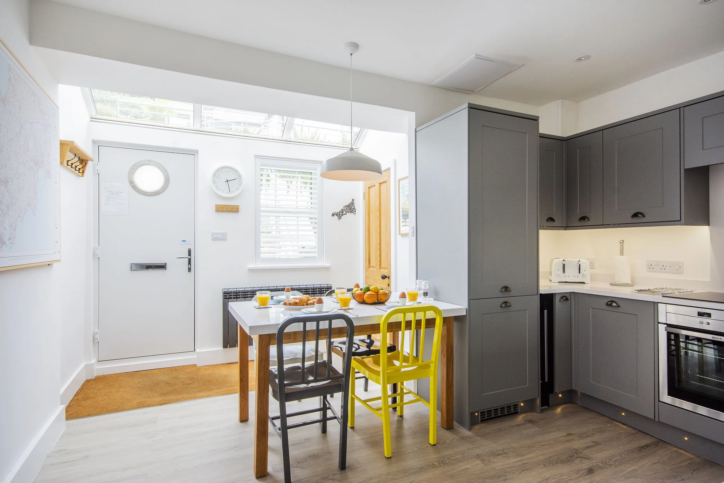 View of the front door to Seafarers cottage into the kitchen and dining room. Light floods in through the glass ceiling in the entrance area. 