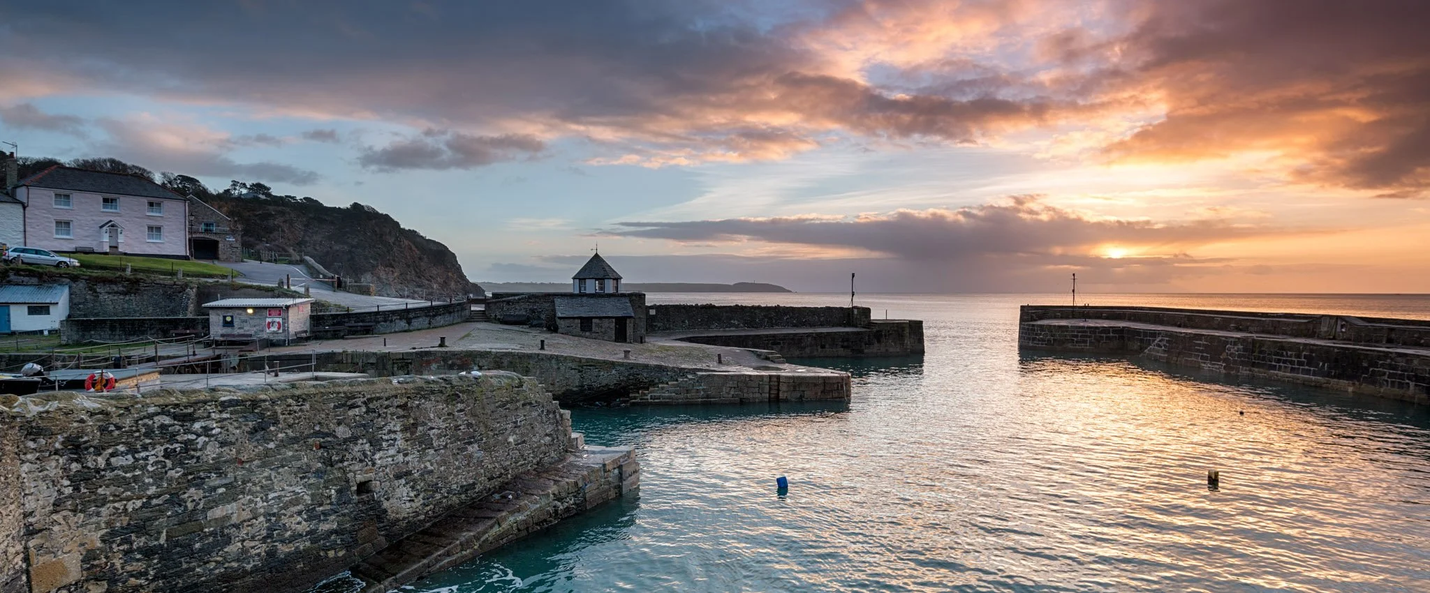 Sunrise view looking out to sea at Charlestown harbour. The sky is beautiful with shades of orange and blue.