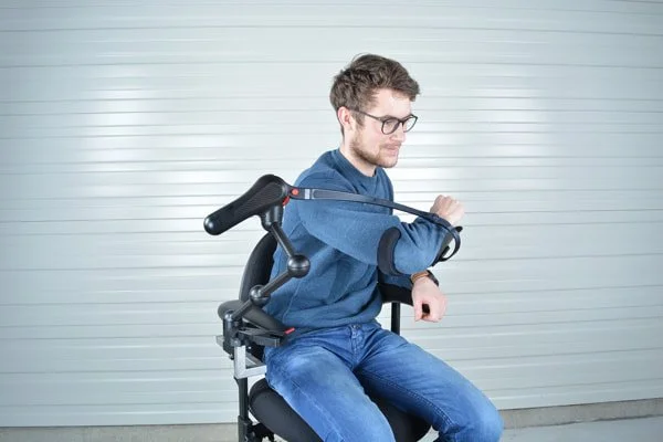 Man sitting in a wheelchair using a robotic arm extension on his arm