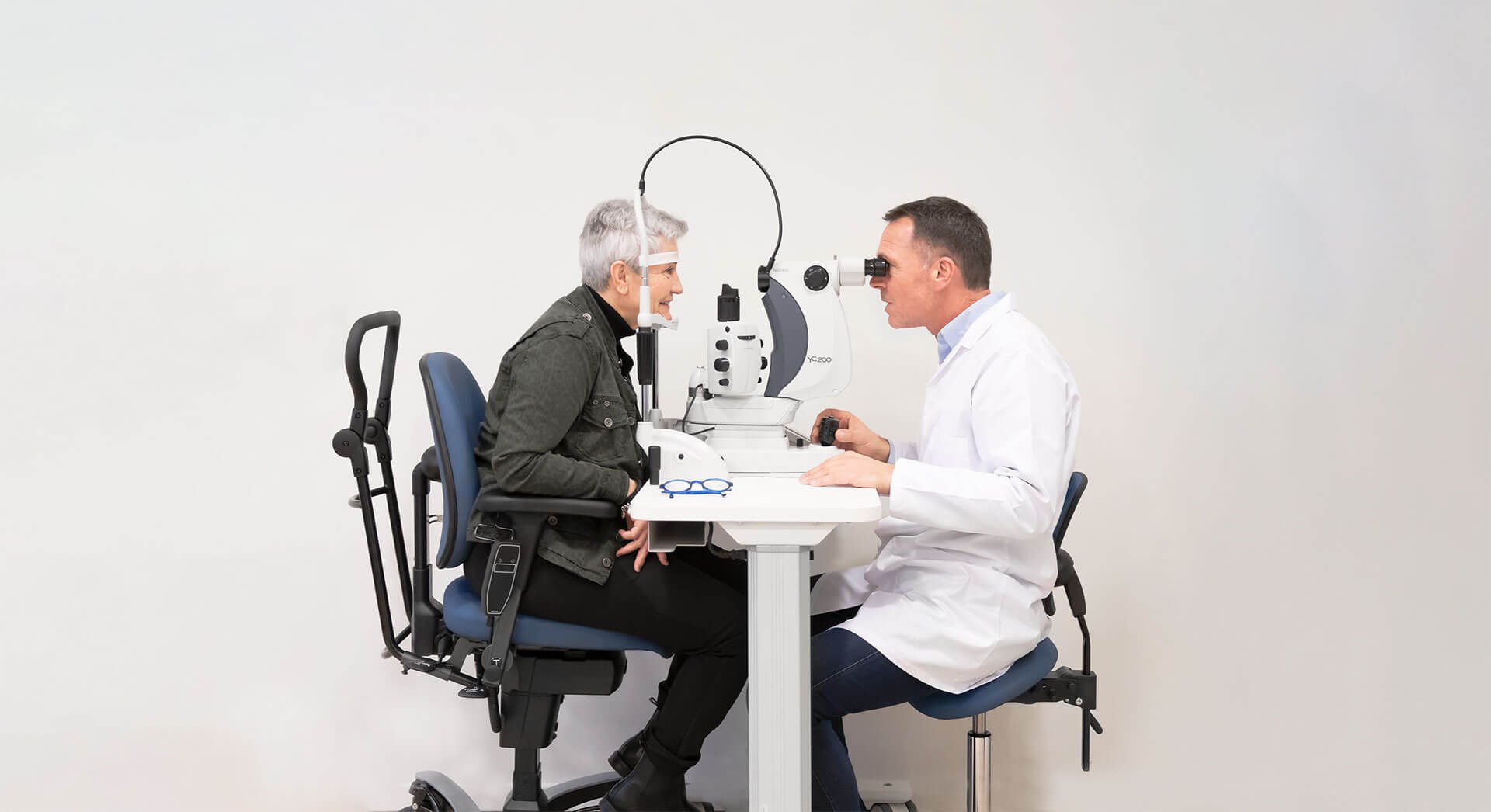 Optometrist examining a patient's eyes with specialized equipment in a clinical setting.