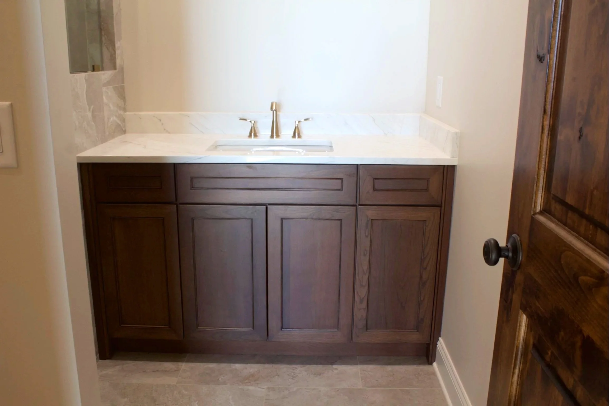 Custom oak bathroom cabinets stained American Walnut, natural stone countertop by Crawford Cabinets