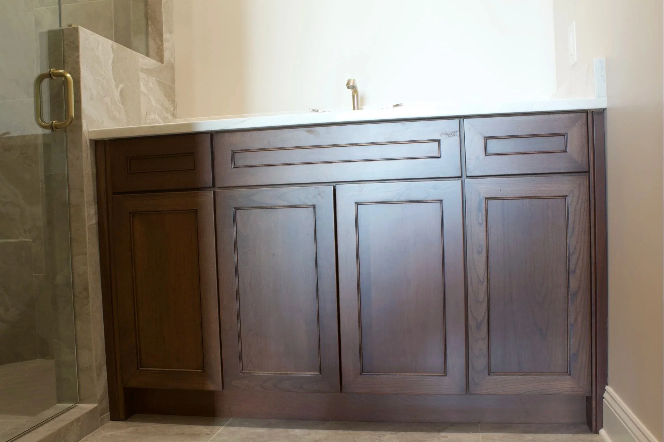 Custom oak bathroom cabinets stained American Walnut, natural stone countertop by Crawford Cabinets