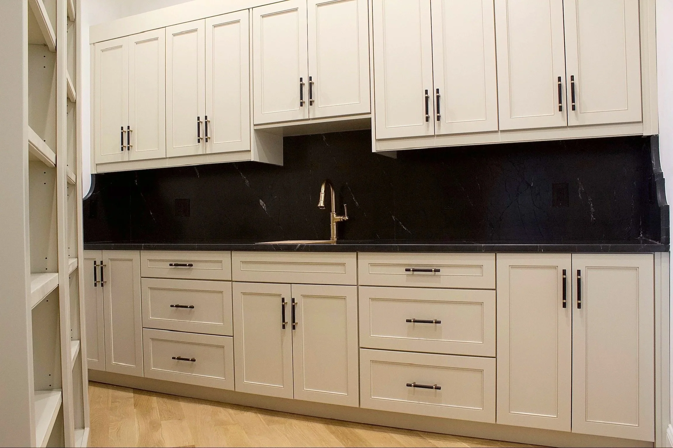 Custom hidden pantry cabinets painted Sherwin Williams Accessible Beige, featuring open shelves and natural stone counter tops by Crawford Cabinets