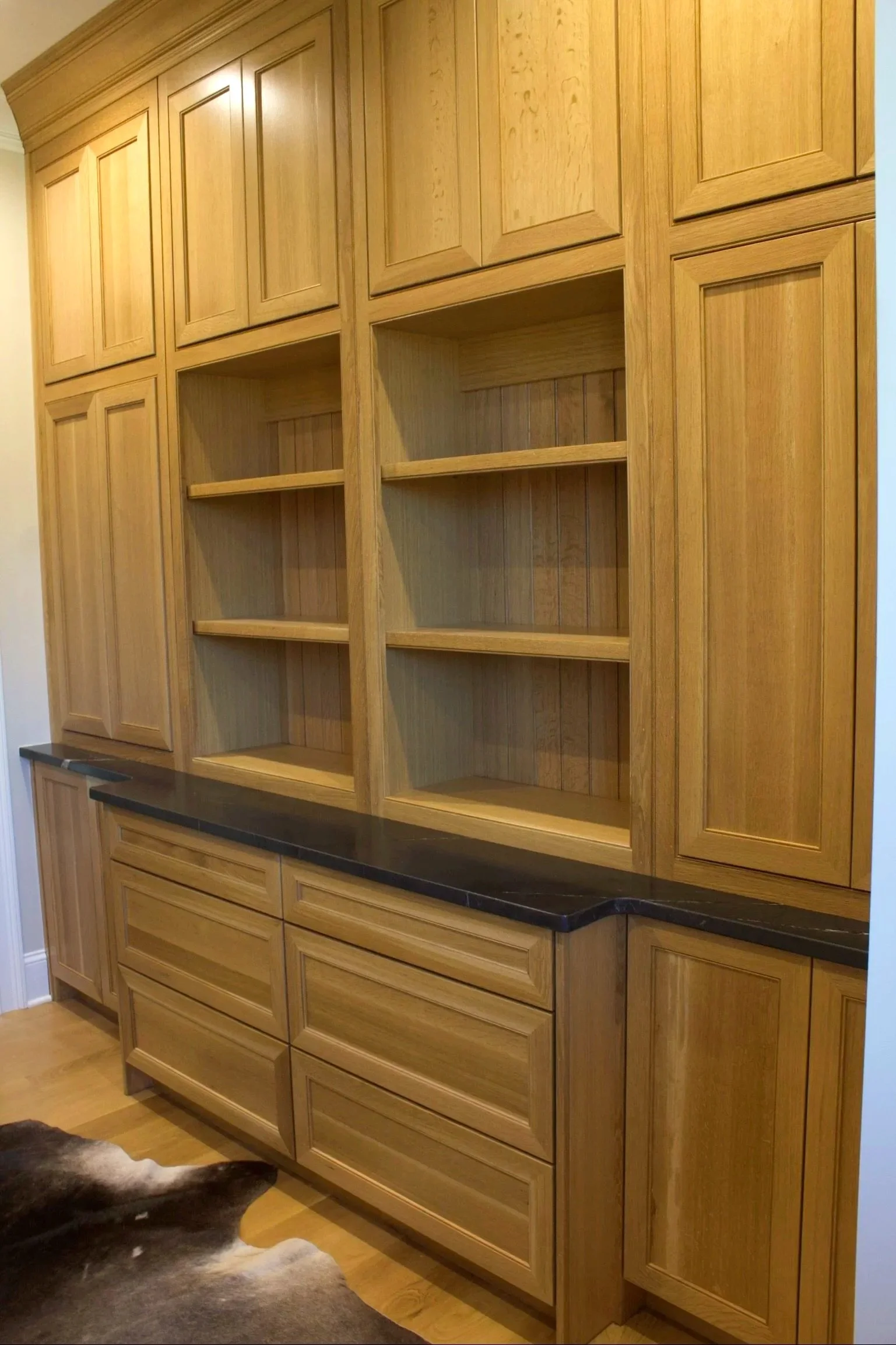 Custom White oak home office with bookshelves, natural finish, and black stone counter top by Crawford Cabinets