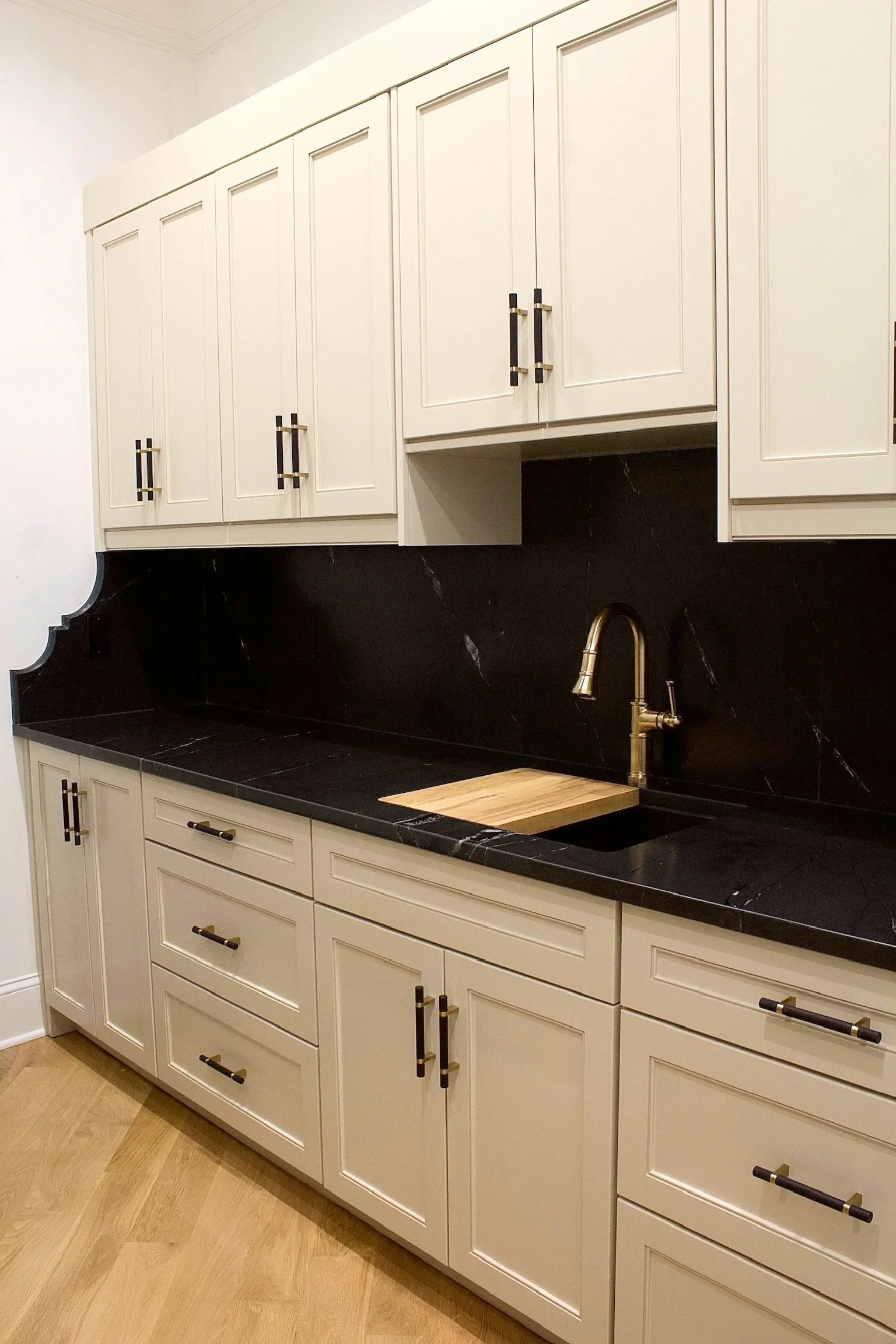 Custom hidden pantry cabinets painted Sherwin Williams Accessible Beige, featuring open shelves and natural stone counter tops by Crawford Cabinets