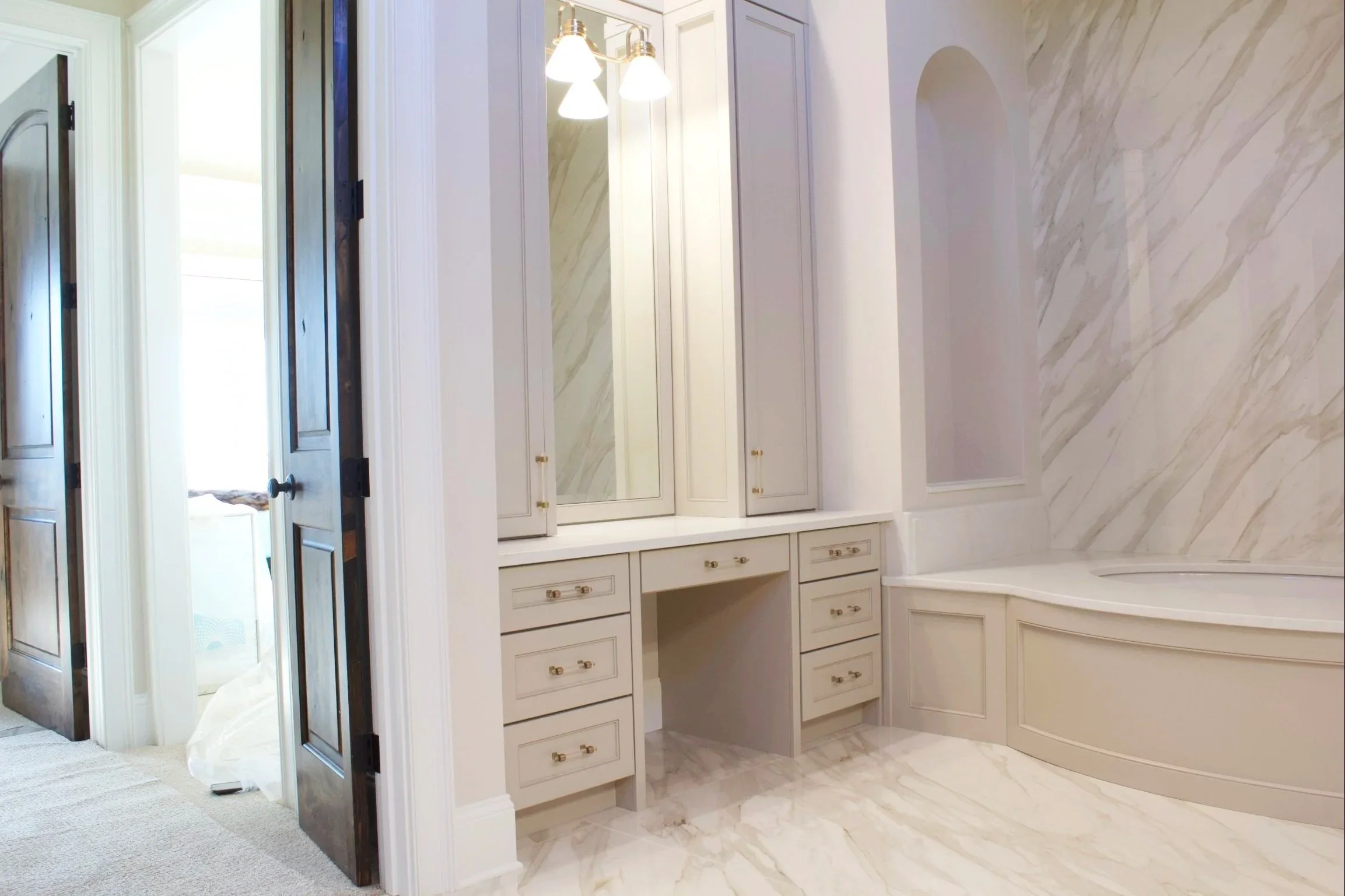 Custom bathroom cabinets painted Sherwin Williams Anew Gray, featuring roll-out laundry hampers, double sinks, and natural stone countertops by Crawford Cabinets