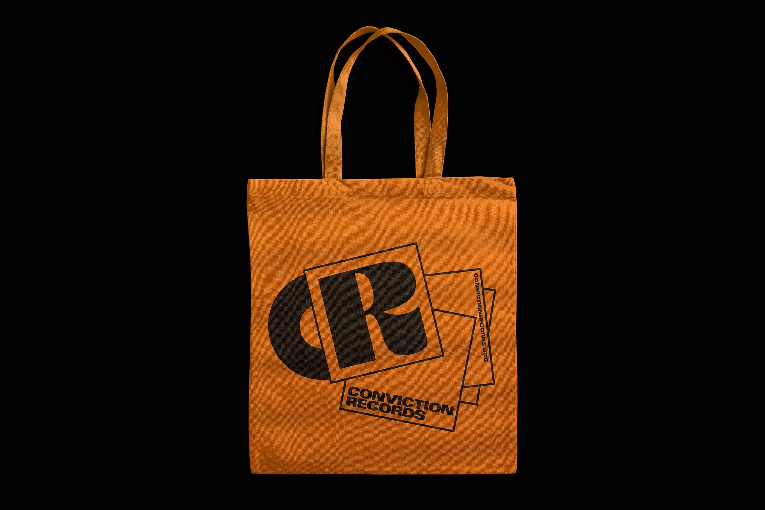 Orange tote bag with black logos and text reading 'Conviction Records' and a website URL, set against a black background.