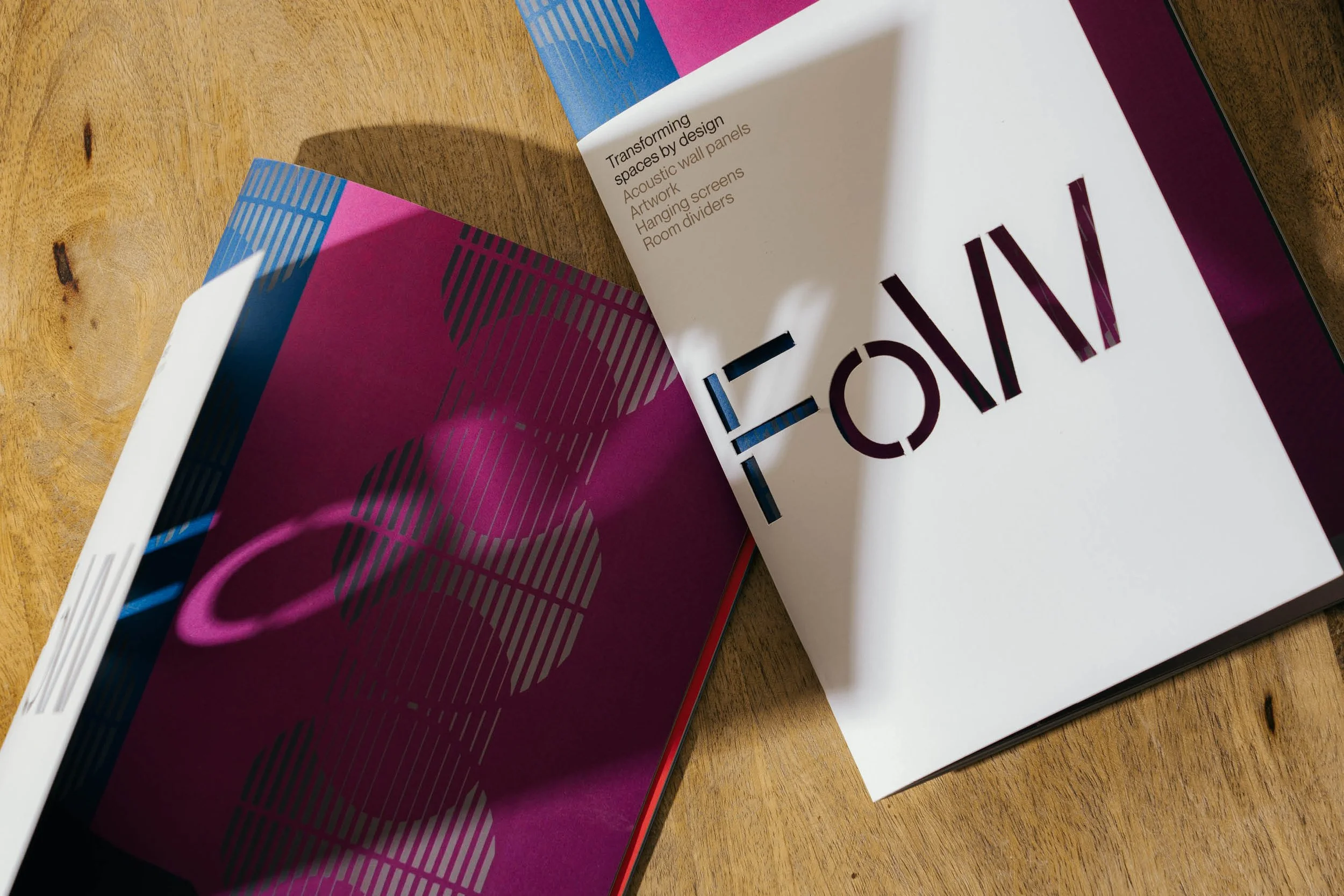 Open magazine on a wooden table with colorful abstract design and large bold text.