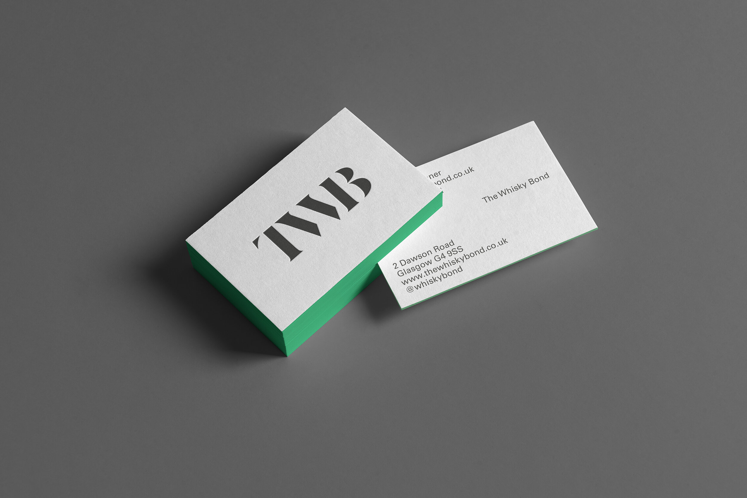 A stack of business cards with the logo 'TVB' in bold black letters, and a few cards spread out showing an address and contact information on a gray background.