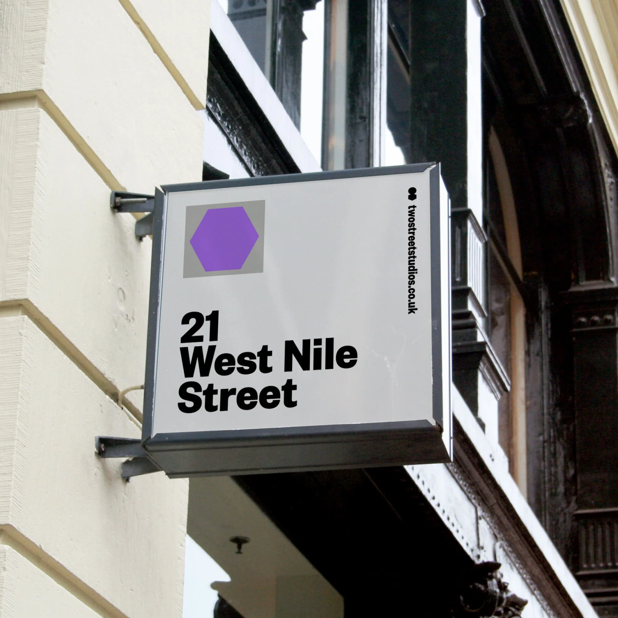 Street sign displaying the address 21 West Nile Street in bold black letters, with a purple hexagon logo and a website URL twostreetstudios.co.uk.