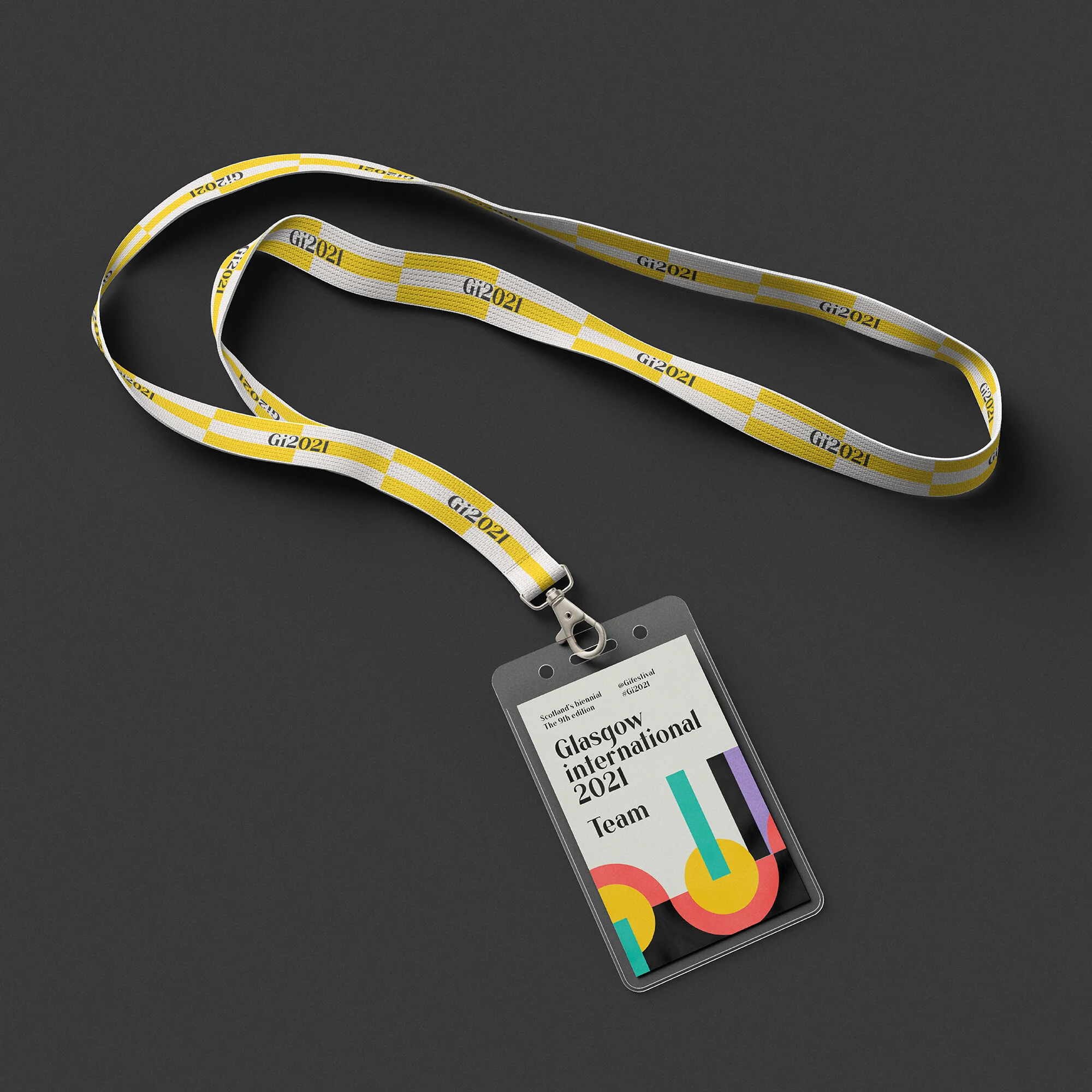 Lanyard with a badge holder containing a card for the Glasgow International 2021 team event, displayed against a dark background.
