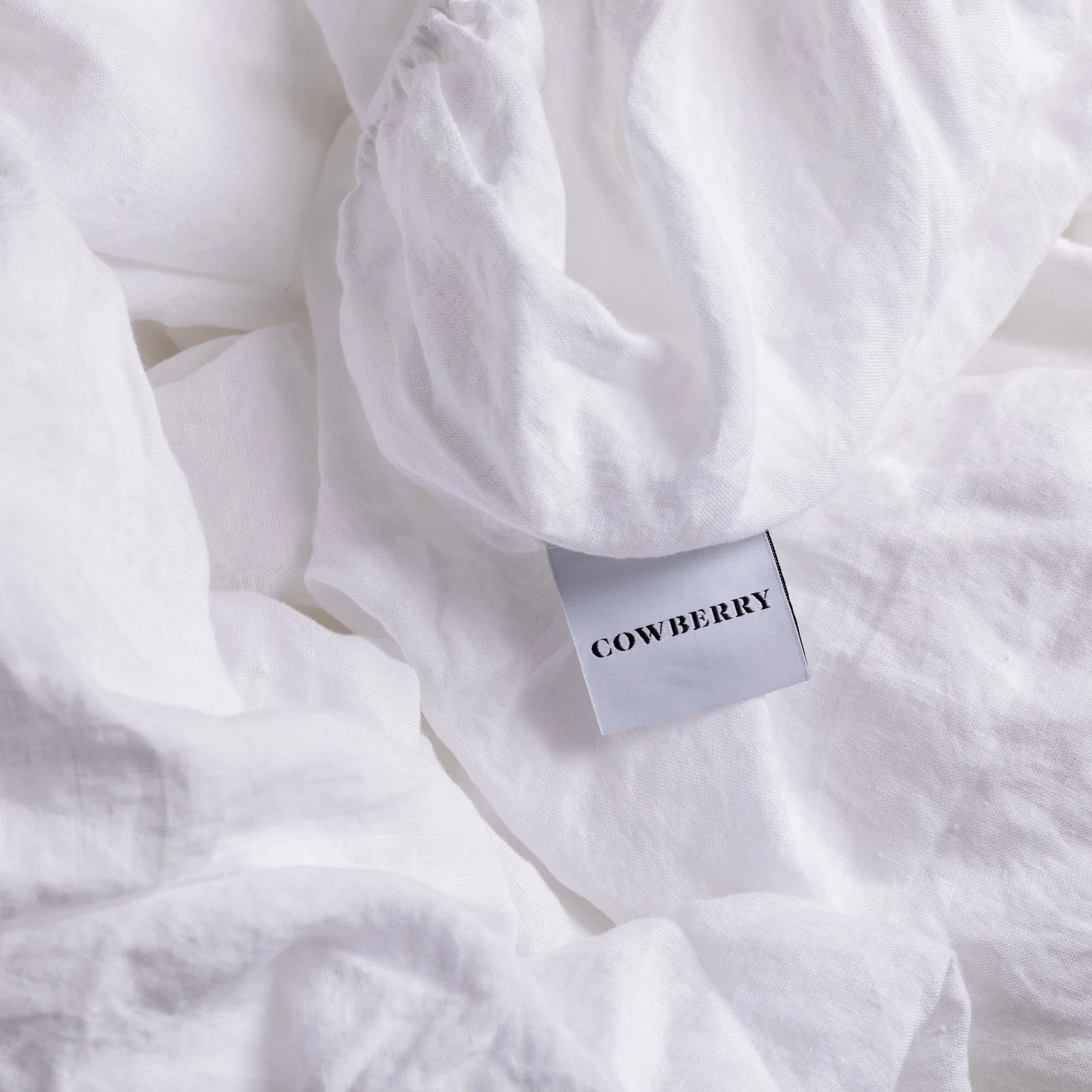 Close-up of white fabric with a black label that reads 'COWBERRY' partially hidden among the material.