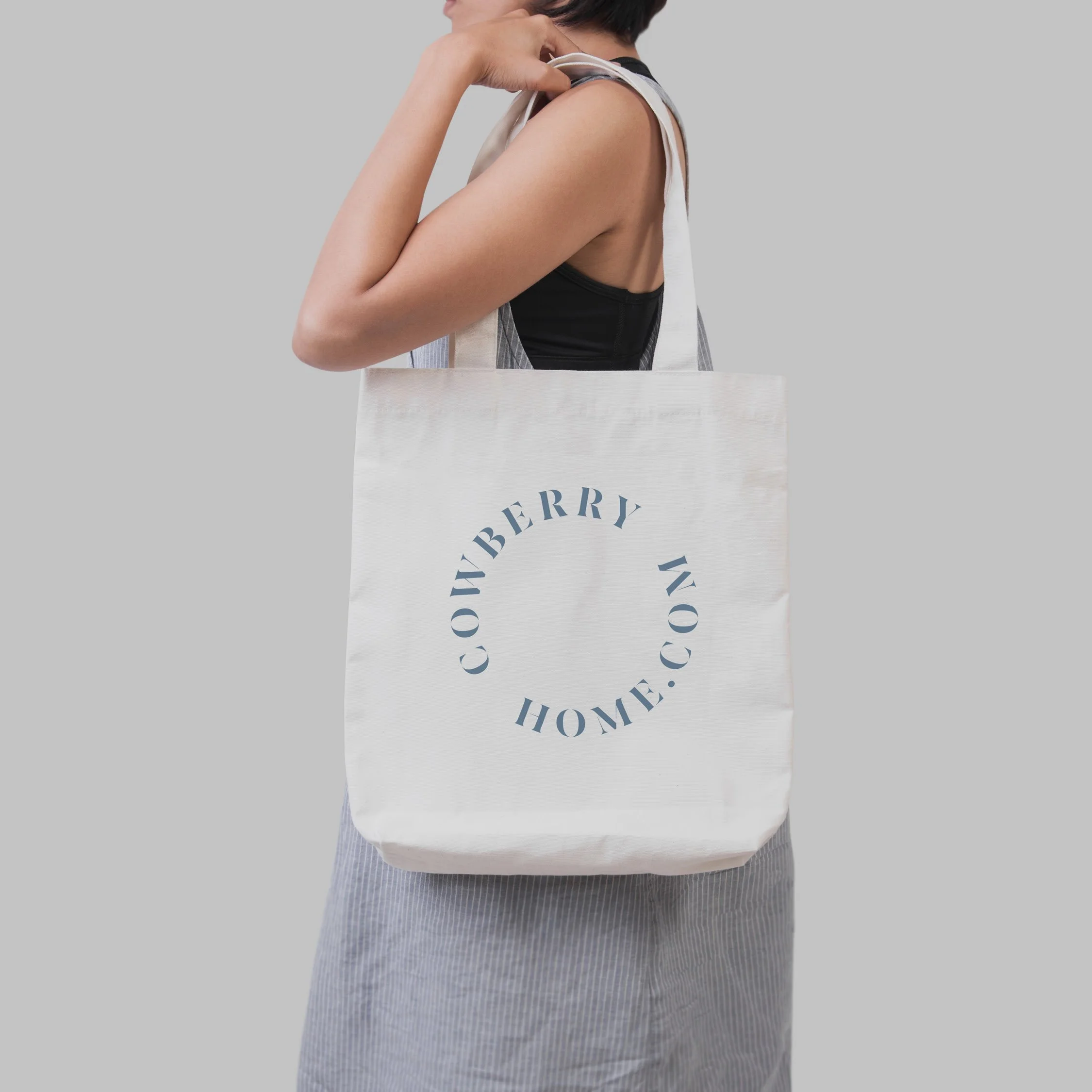 Person holding a white tote bag with the website 'CONVEYERBYHOME.COM' printed in a circle on the front.