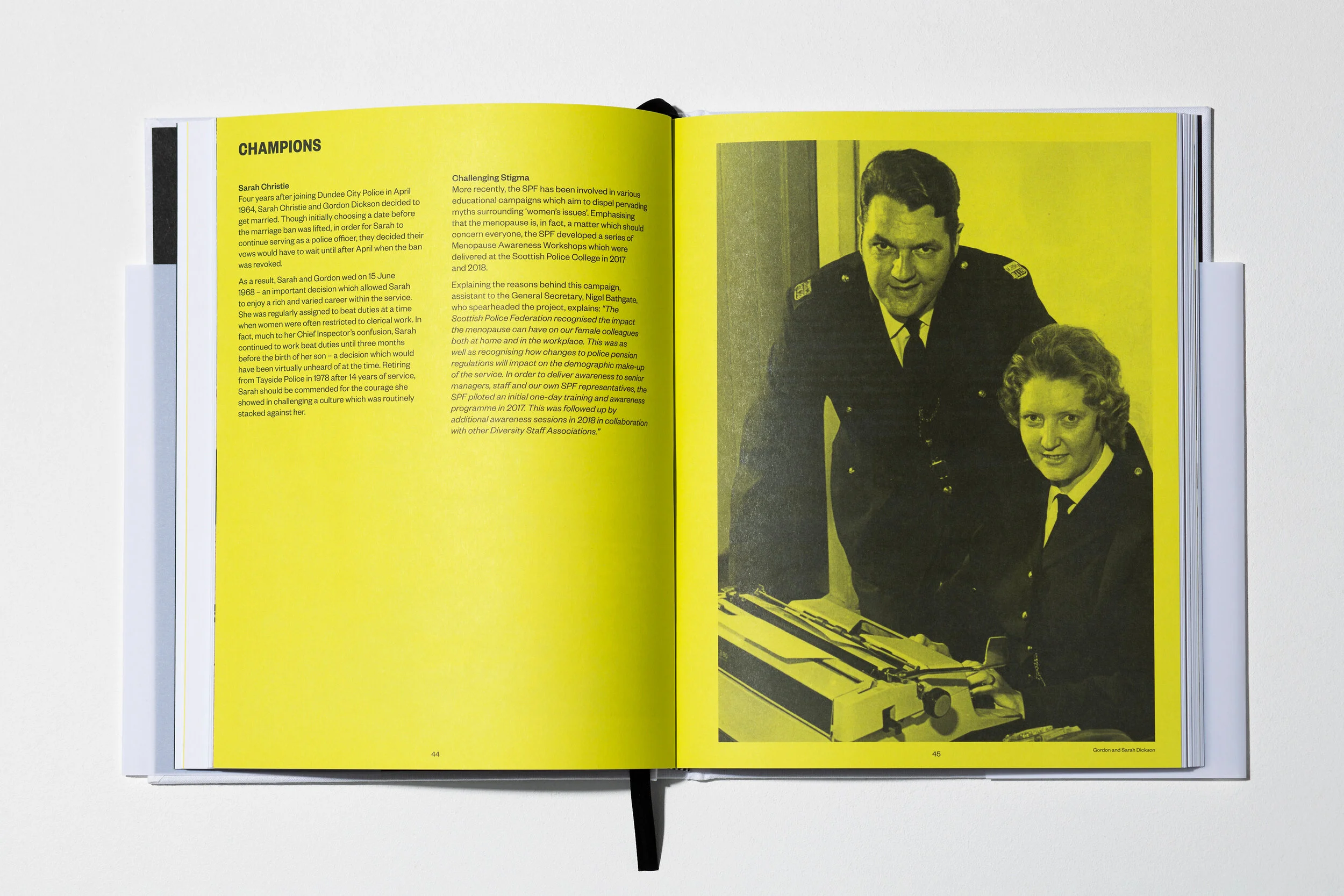 Open book with yellow pages, one page containing text about Sarah Christie and Gordon Dickson, and the opposite page featuring a black and yellow photograph of two police officers, a man in uniform and a woman, sitting with a typewriter on the table.