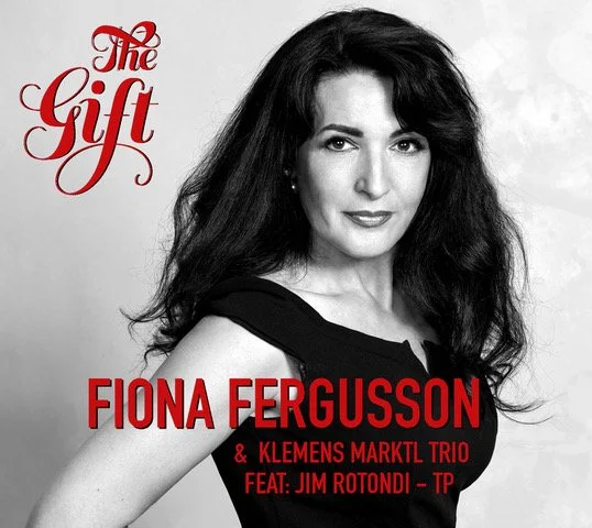 Schwarze und weiße Aufnahme einer Frau mit langem, gewelltem Haar, auf dem Bild stehen die Titel 'The Gift', 'Fiona Fergusson' und 'Klemens Marktl Trio feat. Jim Rotondi - TP'.