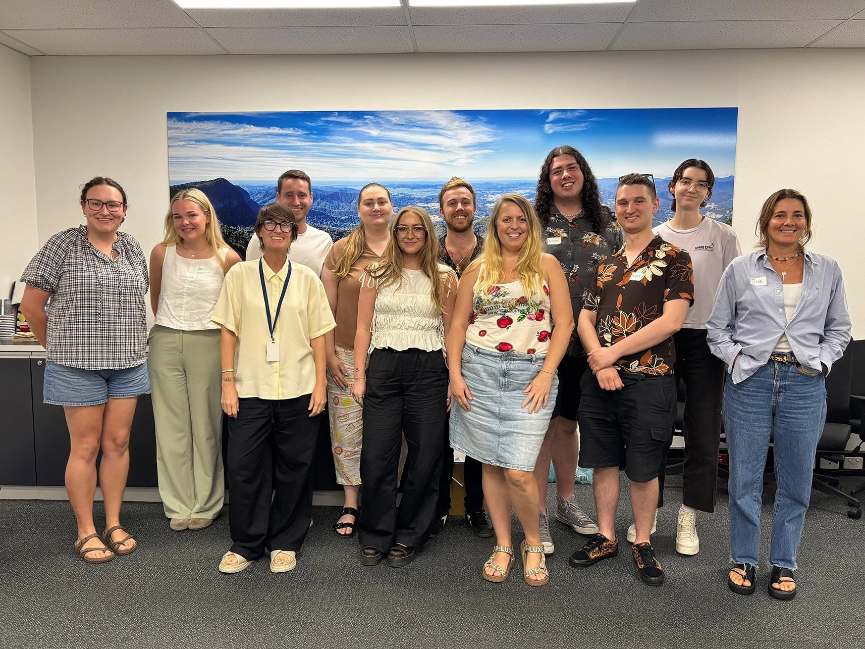 A group of fifteen people standing together in an office, experiencing an uplifting masterclass regarding film and crew