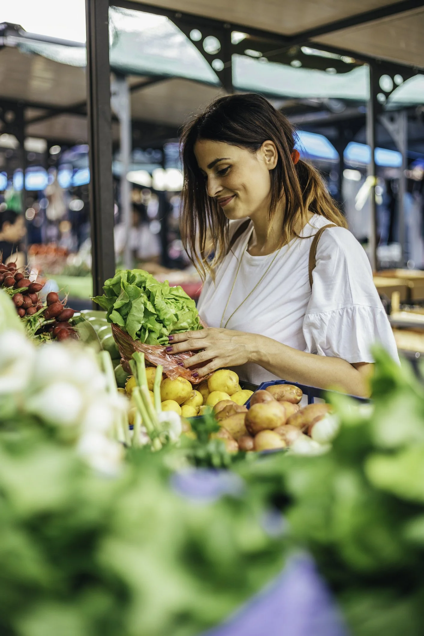 Une femme achetant des légumes biologiques au marché.