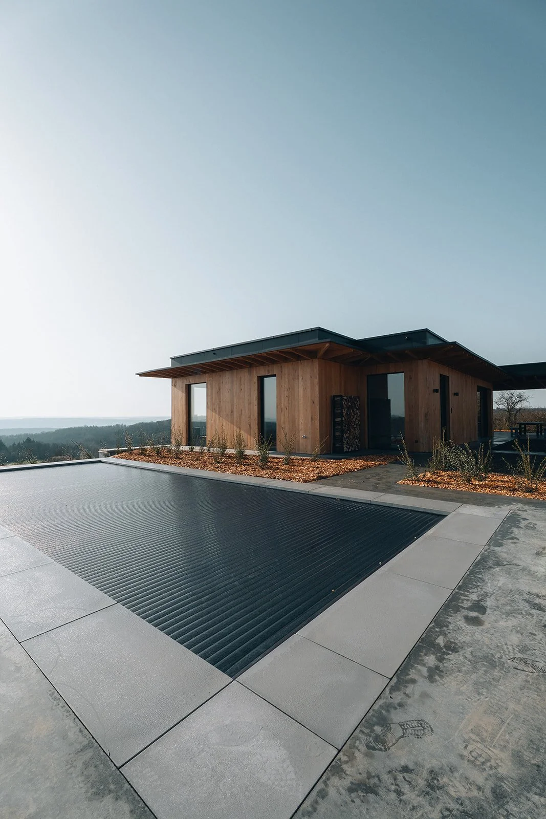 Une maison moderne en bois avec une piscine et un paysage naturel en arrière-plan.
