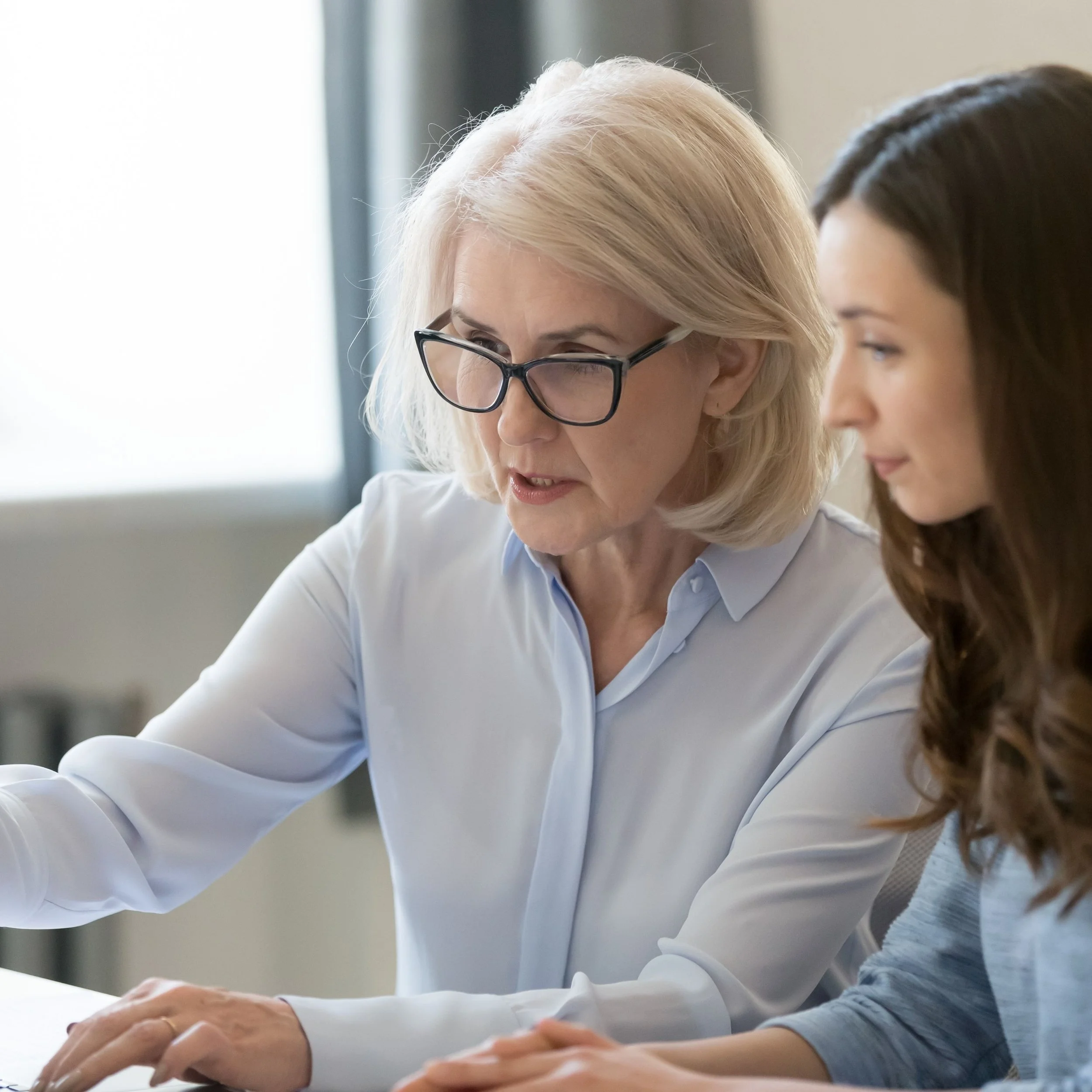 Two colleagues reviewing information together on a computer.