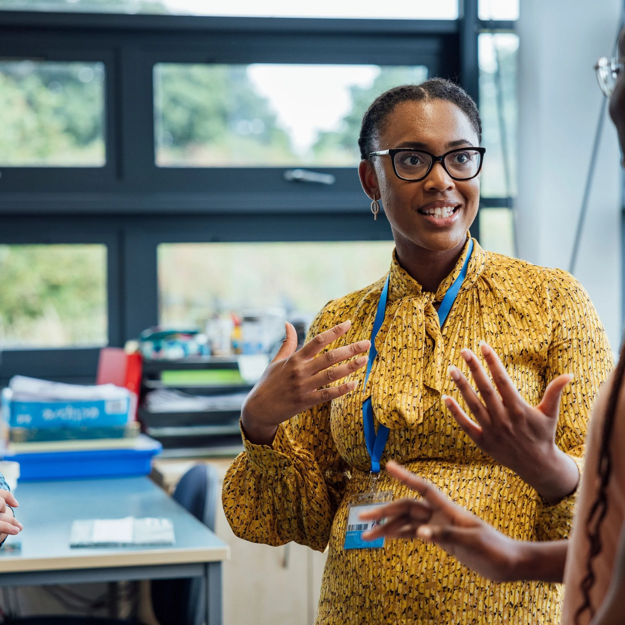 Staff member wearing a lanyard and gesturing during a conversation.