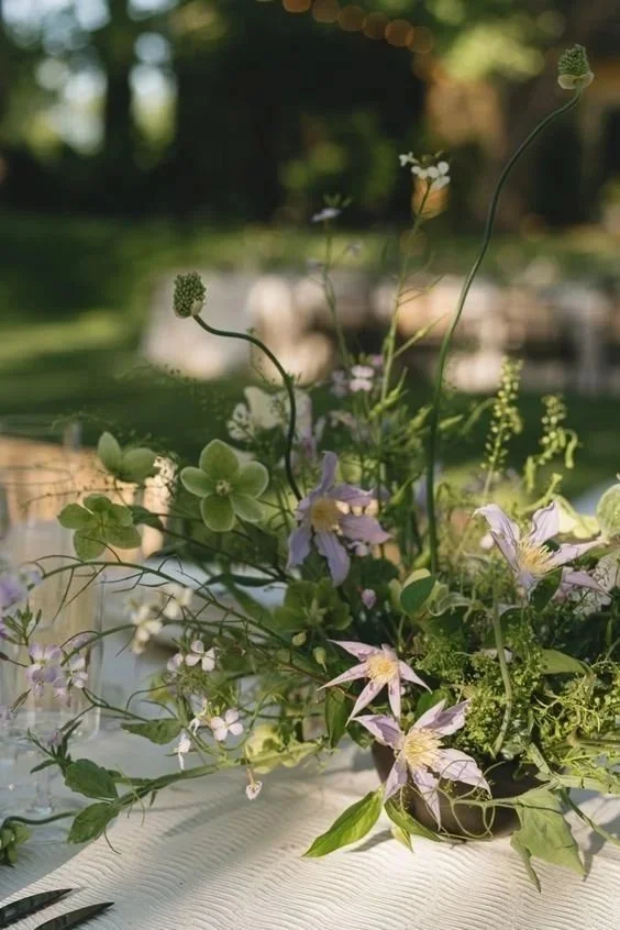 Ramo de flores diversas, incluyendo margaritas, con un fondo difuso en un entorno al aire libre.