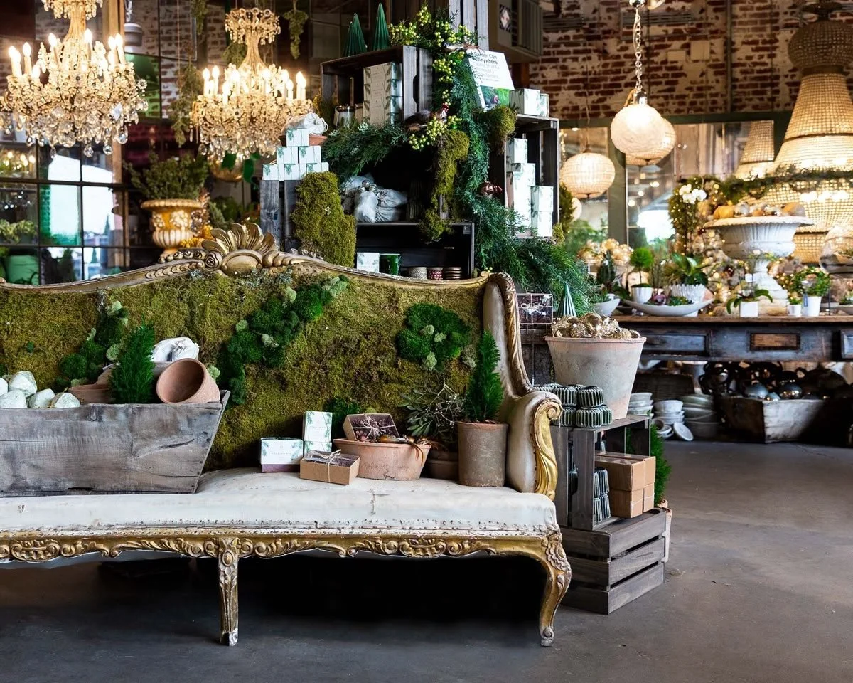 Decoración de tienda con muebles vintage, muchas plantas, candelabros de cristales y lámparas de araña