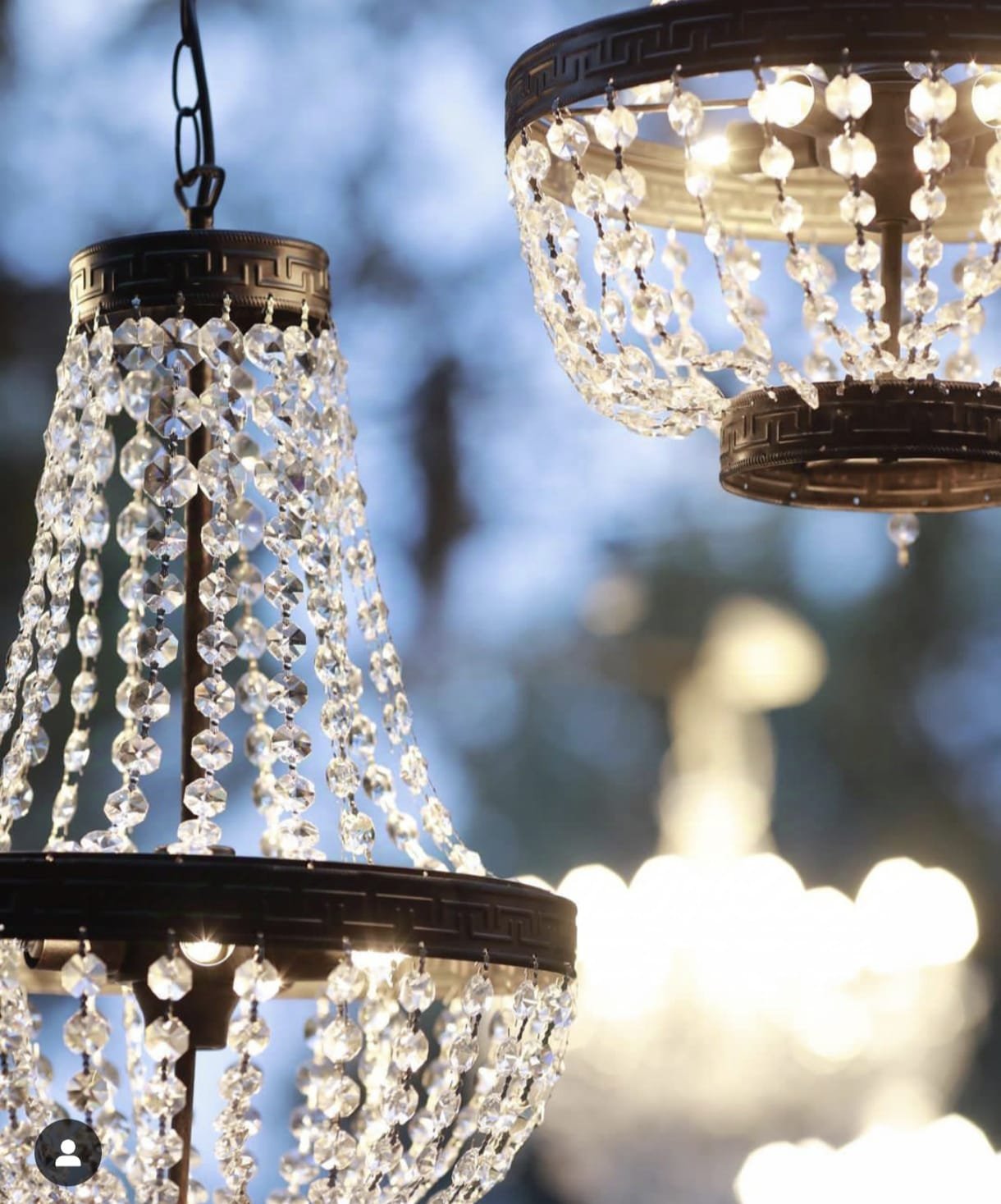 Dos candelabros colgantes con cristales brillantes en un ambiente exterior.