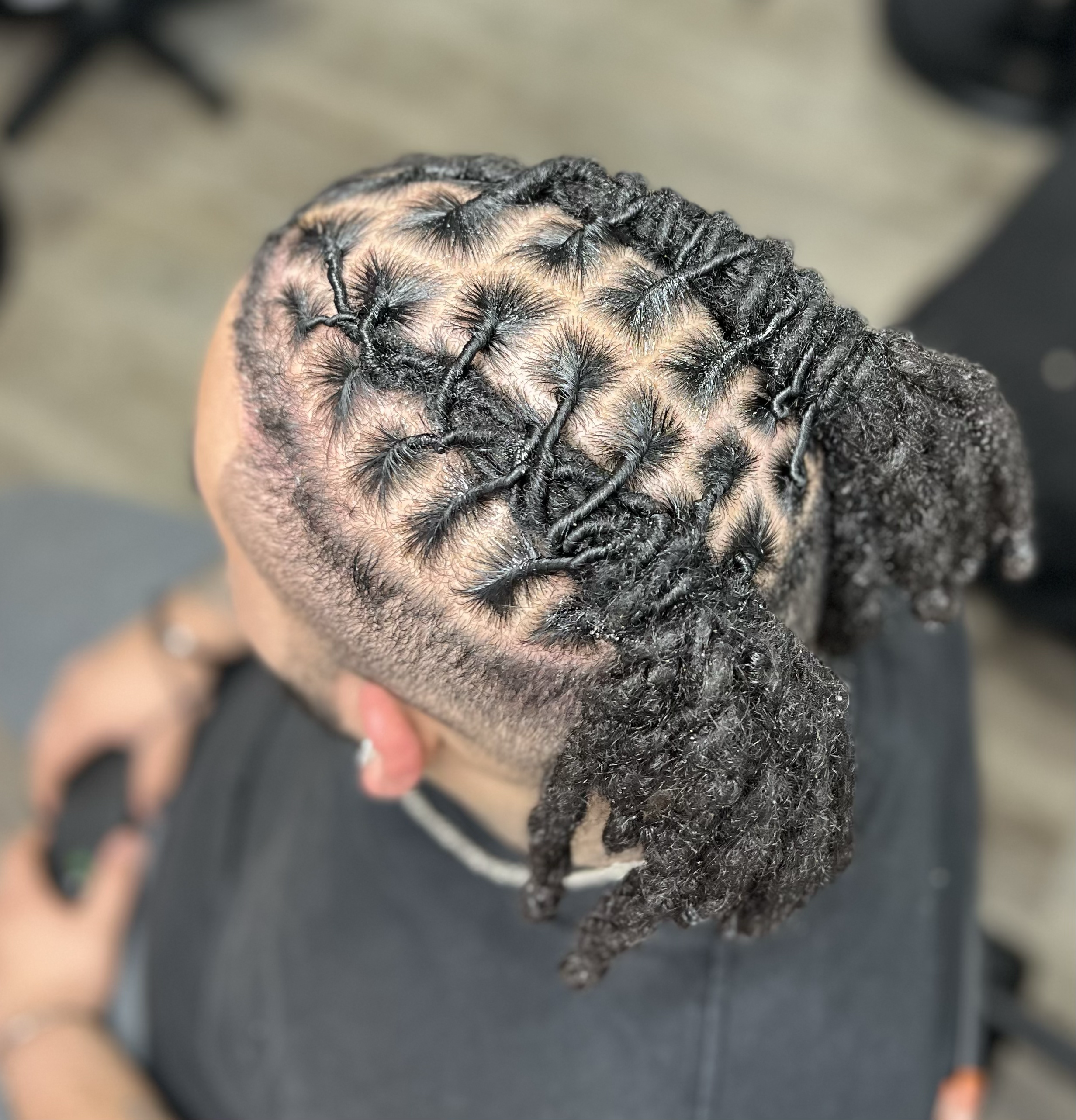 A person with freshly styled dreadlocks and curly hair, viewed from above.
