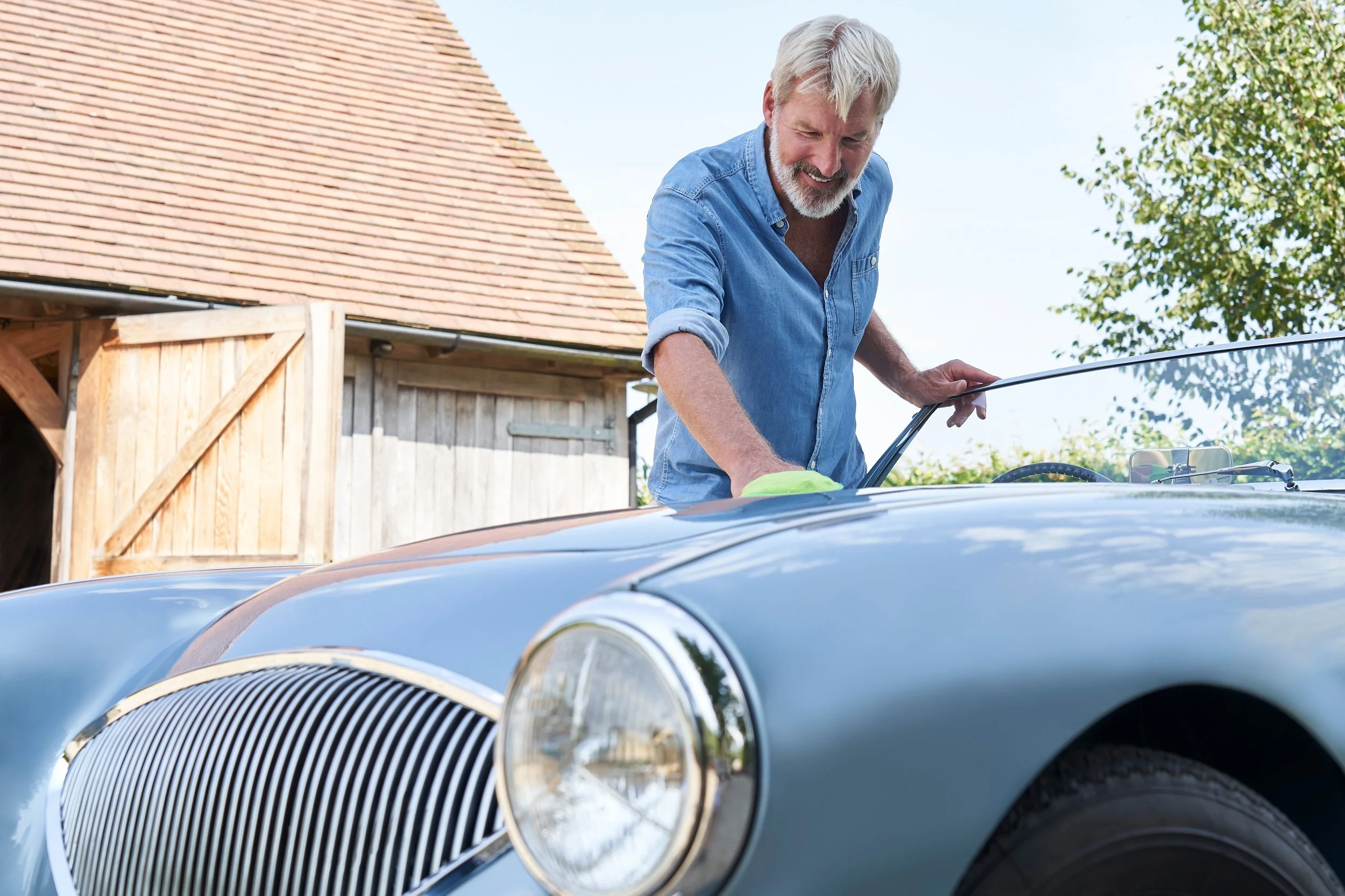 mature man polishing classic car