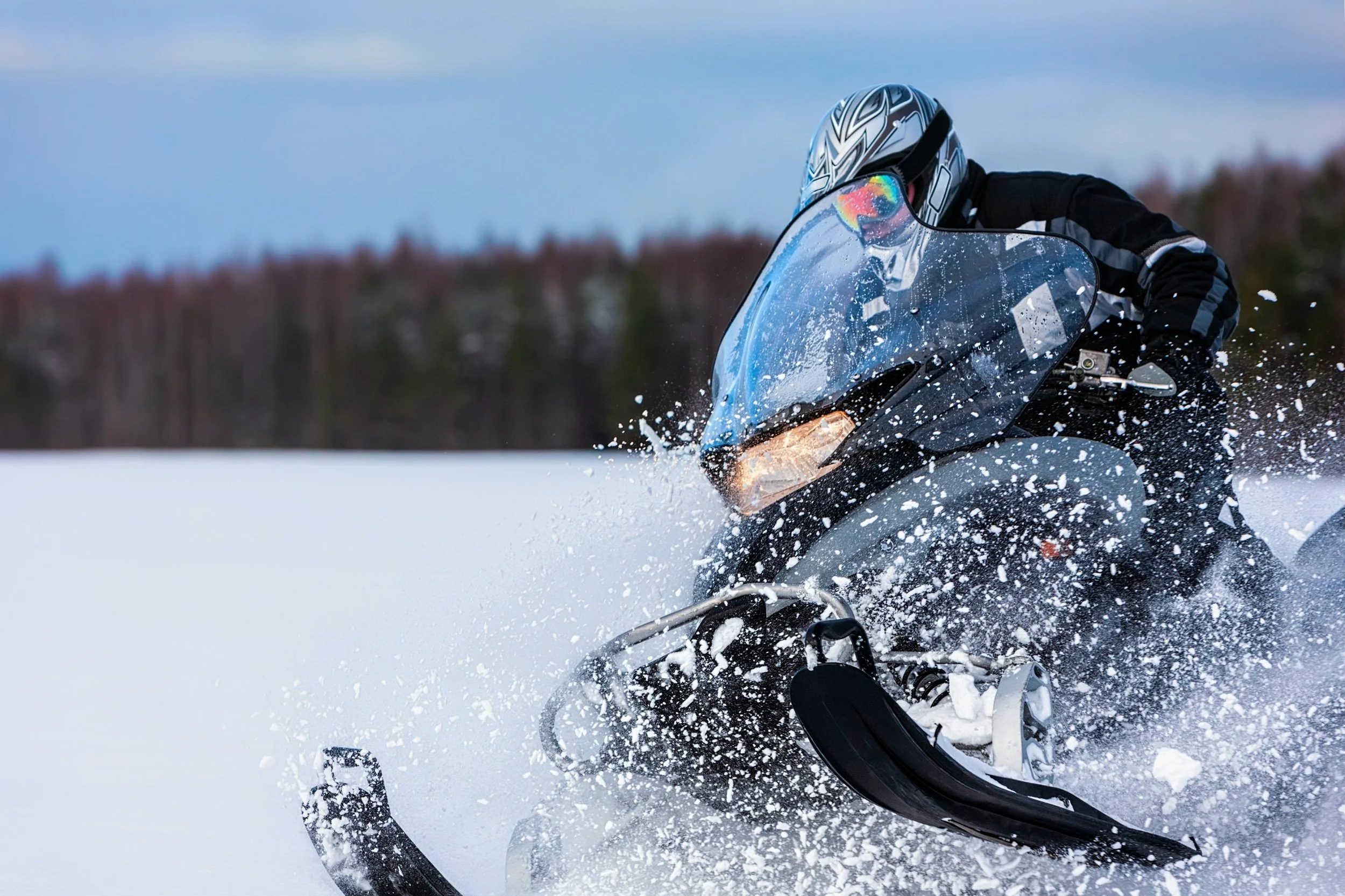person driving a snow mobile in the winter on the snow